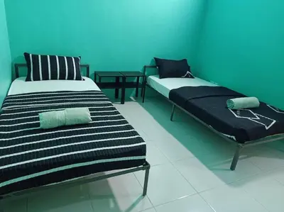 two beds in a room with blue walls at Bota TheDaun Homestay Taman Indera in Kampung Bota Kiri