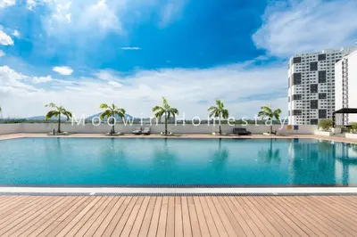 a large swimming pool with palm trees and a building at Meritus Family Comfy Deluxe Home in Perai