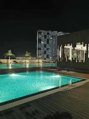 a large swimming pool at night in a city at Meritus Family Comfy Deluxe Home in Perai