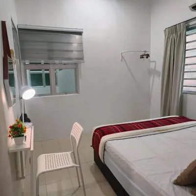 a bedroom with a bed and a table and a chair at Taiping Holiday Home 2 in Taiping