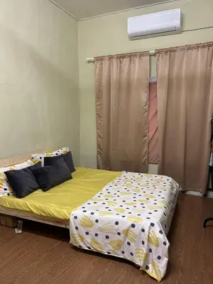 a bedroom with a bed with yellow sheets and a window at Homestay Abah At in Baling