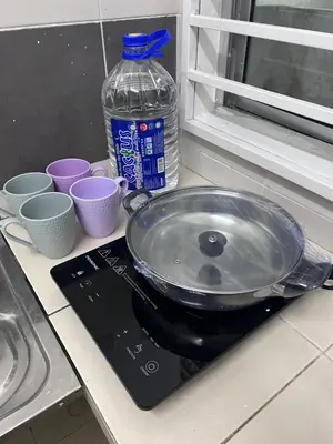a pan on a counter with cups and a bottle of water at Ayaan Cozy Homestay Cameron Highland in Tanah Rata
