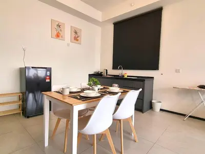 a dining room with a table and white chairs at 2 Rooms Apartment, 4 to 5 pax at Urban Suites by SuperStay in Jelutong