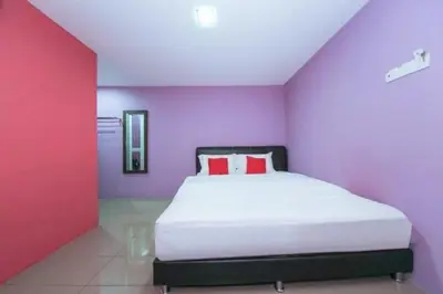 a bedroom with a white bed with purple walls at The Inn Hotel in Teluk Intan