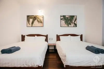 two beds in a room with white sheets and blue pillows at Ipoh Cozy 27 Pool Villa 6B5B 30 pax by Verve in Ipoh