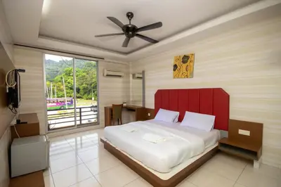 a bedroom with a bed with a red headboard and a window at JQ Happy Lumut Hotel in Lumut
