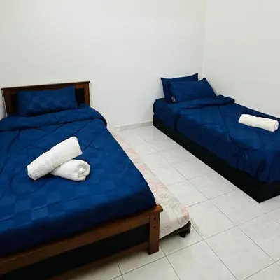two beds in a room with blue sheets and towels at MayiiVip Homestay - Menglembu in Ipoh