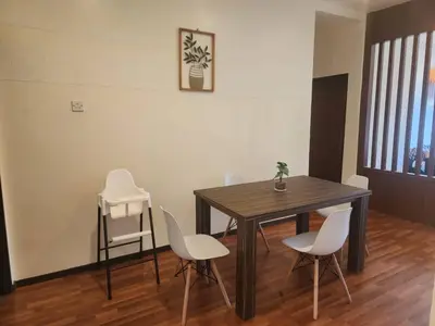 a dining room with a wooden table and white chairs at Iris Bougainvillea Cameron's in Tanah Rata