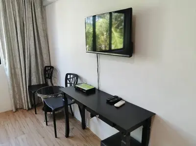 a room with a table and a television on the wall at C 23 Lot 10 Pangkor Leisure Beach Studio in Pangkor