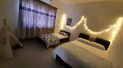 a bedroom with two beds and lights on the wall at Cozy House in Taiping in Taiping