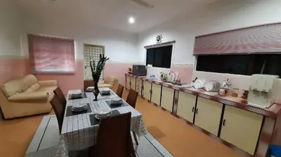 a living room with a table and a kitchen at Cozy House in Taiping in Taiping