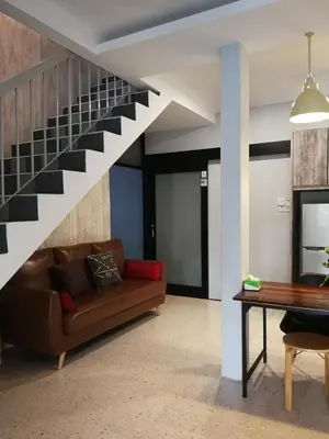 a living room with a couch and a staircase at Check-Inn Guesthouse in Ipoh
