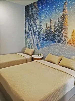 two beds in a room with a painting on the wall at Check-Inn Guesthouse in Ipoh