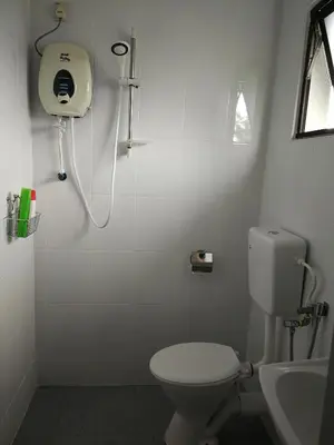 a white bathroom with a toilet and a sink at Check-Inn Guesthouse in Ipoh