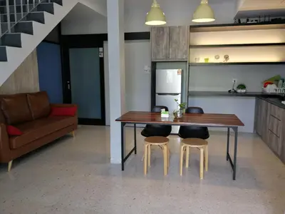 a kitchen with a table and two stools and a couch at Check-Inn Guesthouse in Ipoh