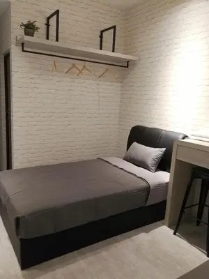 a bedroom with a bed and a white brick wall at Check-Inn Guesthouse in Ipoh