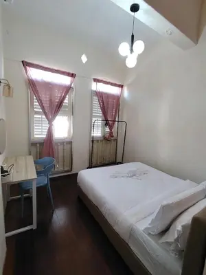 a bedroom with a bed and a desk and two windows at Georgetown Guest House 37 in George Town
