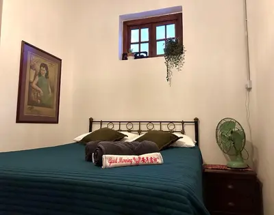 a bedroom with a bed with green sheets and a window at The Gaslight Heritage Residence - NEW in George Town