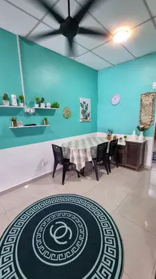a dining room with a table and chairs and a blue wall at MAR Homestay Seri Iskandar in Seri Iskandar