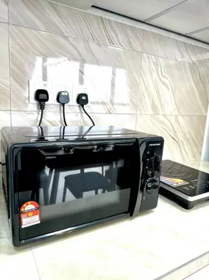 a microwave sitting on a counter next to a laptop at URBAN Georgetown 9Pax 4QueenBed 3Bedroom 2Bath 2carparks in Jelutong