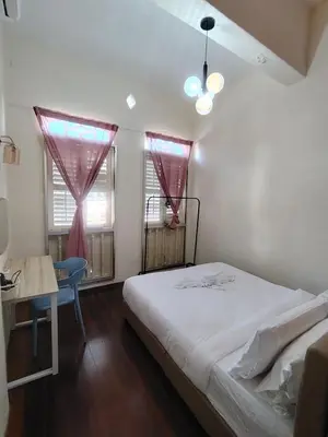a bedroom with a bed and a desk and two windows at Georgetown Cozy 7 Bedrooms 13 Pax in George Town