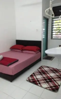 a bedroom with a bed with red pillows and a rug at AL DHAKIYA HOMESTAY KULIM 3r2b in Kulim