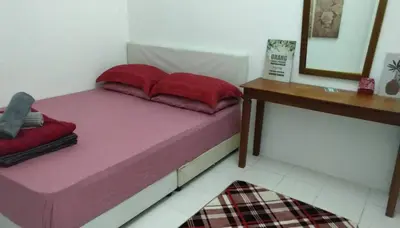 a bed with two red pillows on it in a room at AL DHAKIYA HOMESTAY KULIM 3r2b in Kulim