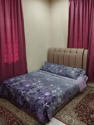 a bed with purple sheets in a room with purple curtains at Homestay Amin 4 Fully Aircond Bedroom & 2 Bathroom in Kulim