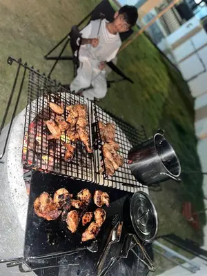 a man is cooking food on a grill at Homestay Aishah in Seri Iskandar