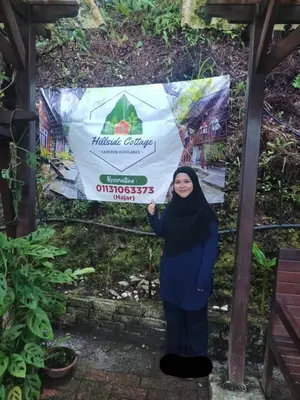 a woman is standing in front of a sign at Hillside cottage tulip room with loteng in Tanah Rata
