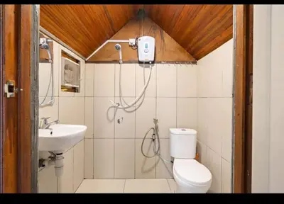 a bathroom with a shower and a toilet and a sink at Hillside cottage tulip room with loteng in Tanah Rata