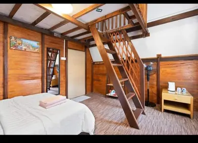a bedroom with a bed and a wooden staircase at Hillside cottage tulip room with loteng in Tanah Rata