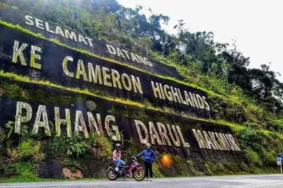 two people on a motorcycle in front of a wall at Hillside cottage tulip room with loteng in Tanah Rata