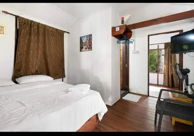 a bedroom with a bed and a desk and a window at Hillside cottage reflesia room in Tanah Rata