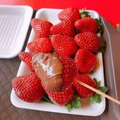 a plate of strawberries and chocolate on a table at Hillside cottage reflesia room in Tanah Rata