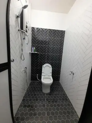 a bathroom with a toilet and black and white tiles at Mukhriz 2 Homestay in Kulim