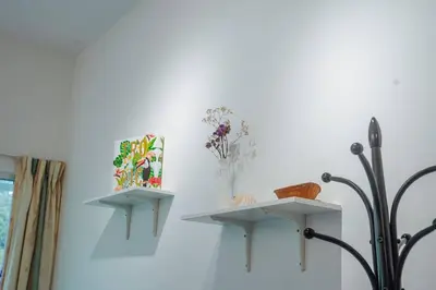 two shelves on a wall with flowers in a vase at Cozy Homestay at Tanah Rata - Moonshot Highlanders in Tanah Rata