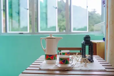 a table with two cups and a vase on it at Cozy Homestay at Tanah Rata - Moonshot Highlanders in Tanah Rata