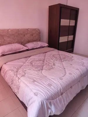 a bed with a pink comforter in a bedroom at Suriati&Fhaiz Homestay in Sungai Petani