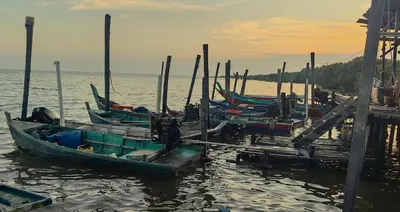 a group of boats docked at a dock in the water at Seaside cottage room stays in Sungai Besar