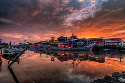 a group of boats docked at a dock at sunset at Seaside cottage room stays in Sungai Besar