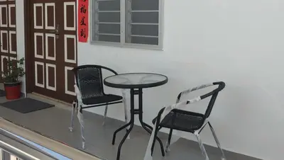a table and two chairs sitting on a balcony at Seaside cottage room stays in Sungai Besar