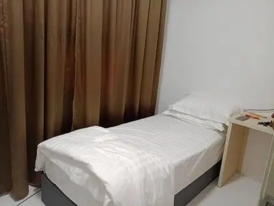 a bedroom with a bed with a curtain and a table at Soho LESTARI in Seri Iskandar