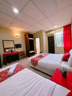 a hotel room with two beds and a desk at De Clinique Hotel in Pangkor