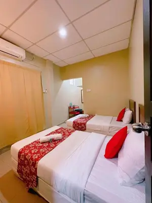 a bedroom with three beds with red pillows at De Clinique Hotel in Pangkor