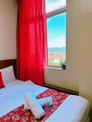 a room with a bed with a red curtain and a window at De Clinique Hotel in Pangkor
