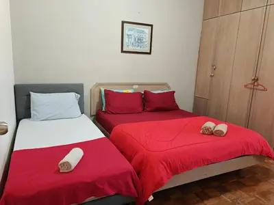two beds in a room with red and white sheets at Bayu Emas Batu Ferringhi Penang in Batu Ferringhi