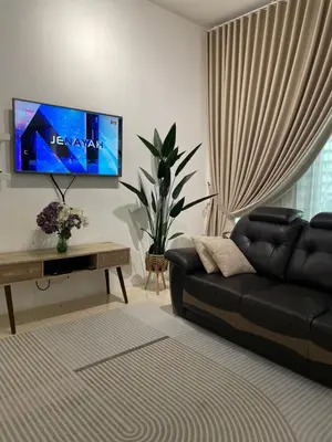 a living room with a black couch and a flat screen tv at Zara Cozy Homestay in Seri Iskandar