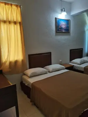 a room with two beds and a picture on the wall at Grand Star Hotel in Batu Ferringhi