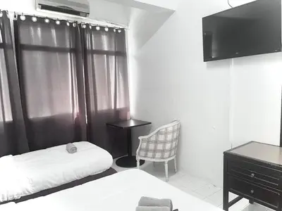 a bedroom with a bed and a chair and a television at Grand Star Hotel in Batu Ferringhi